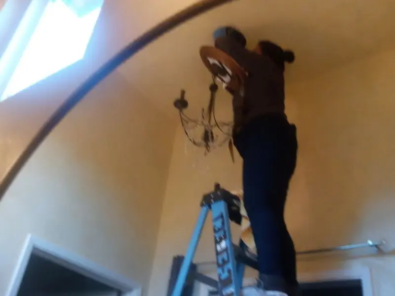 Electrician installing a chandelier in a Astoria residence